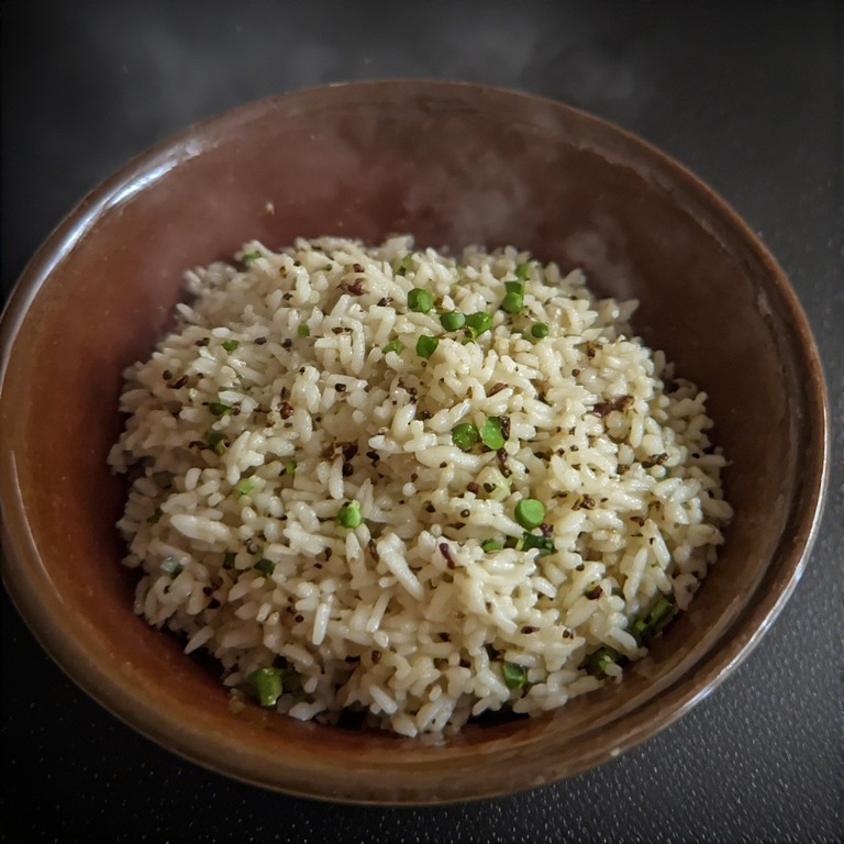 A bowl of white long-grain basmati rice with toasted cumin seeds and fresh green coriander garnish