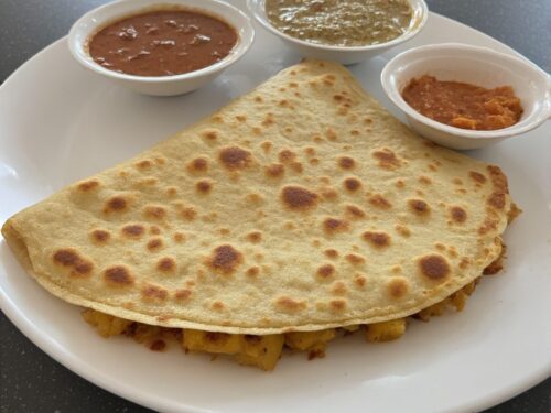 A long, golden-brown crispy dosa served with a side of coconut chutney and tomato chutney